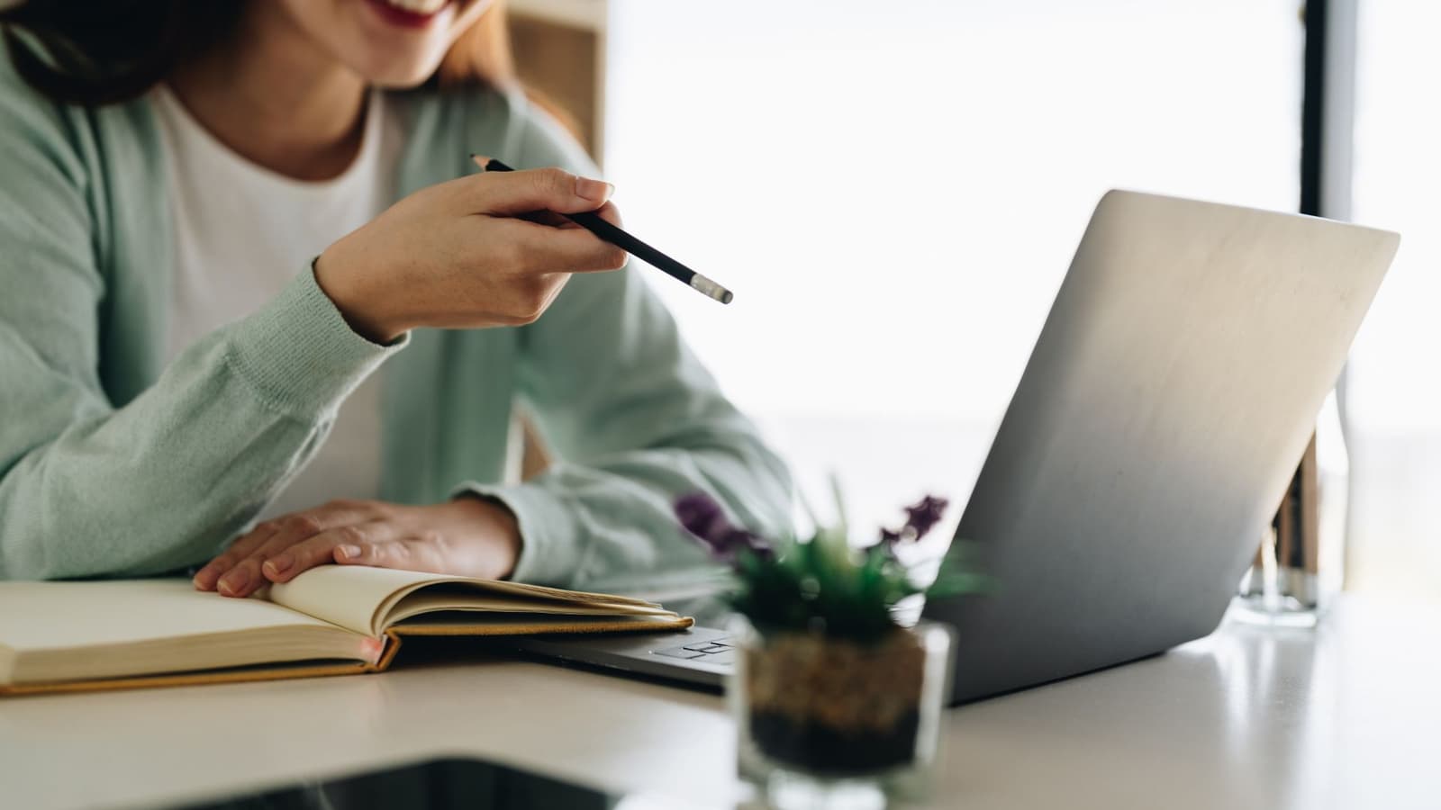 A healthcare professional working on her CV at a laptop with a notebook and pen