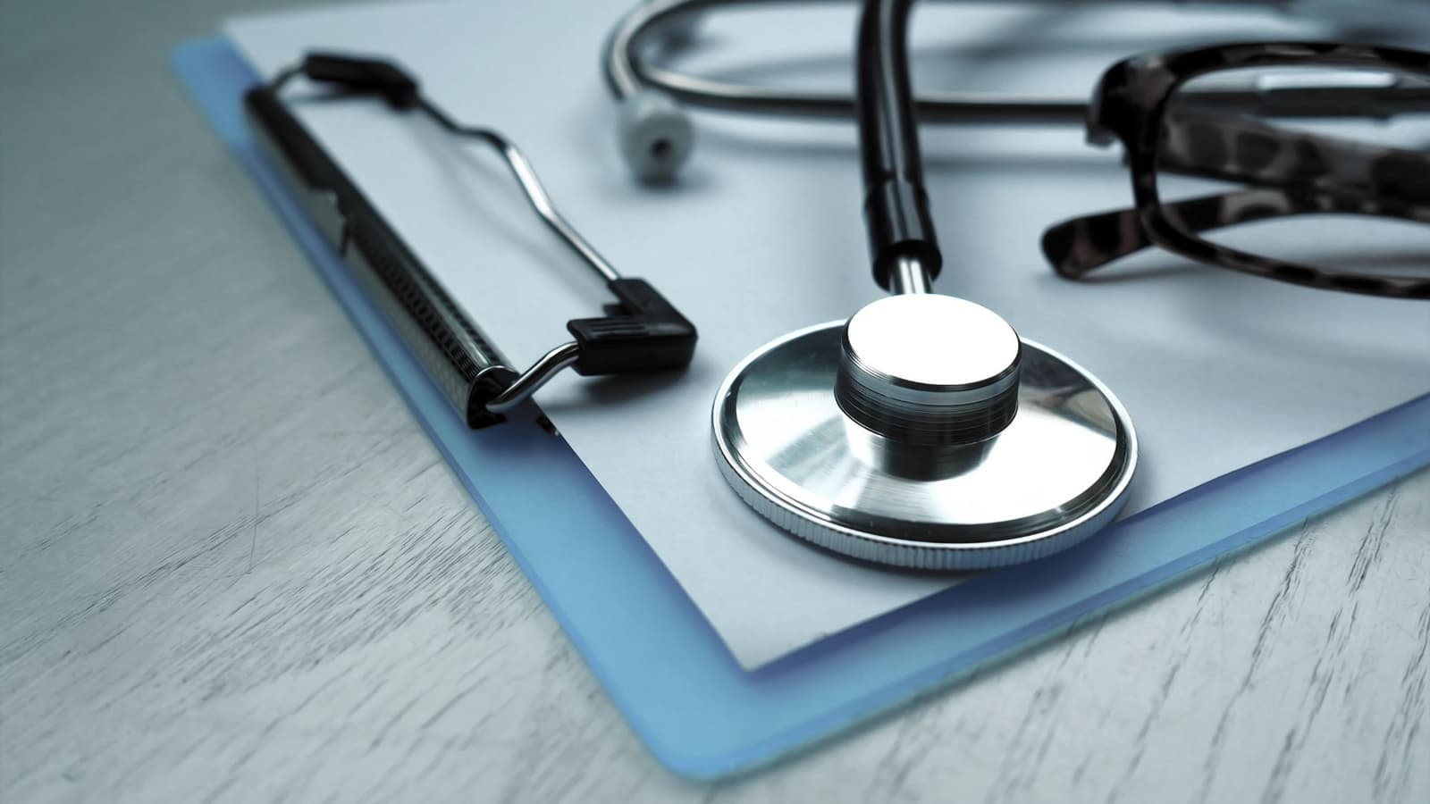 A stethoscope resting on a clipboard of clinical paperwork