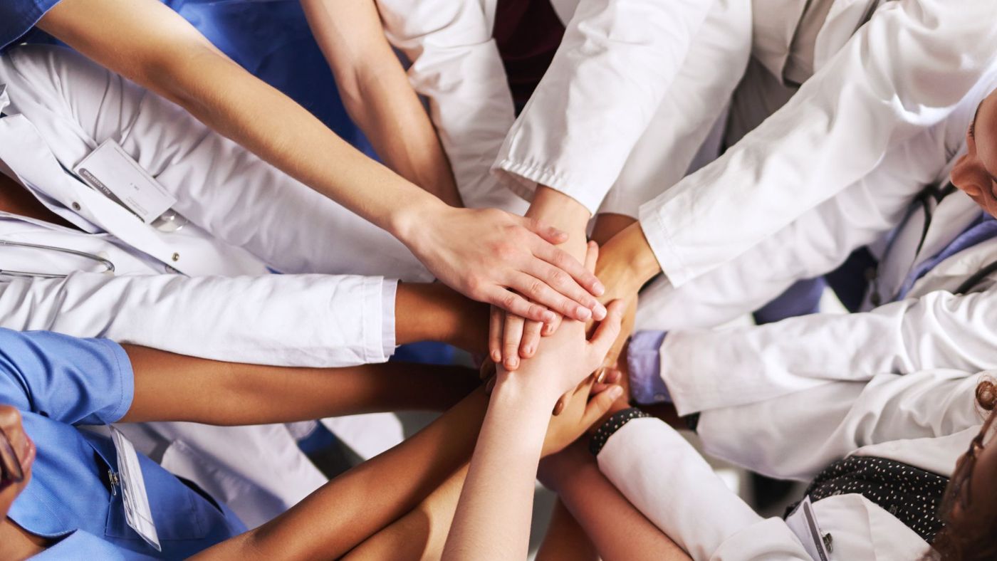 Healthcare workers stacking their hands together in a show of teamwork and support